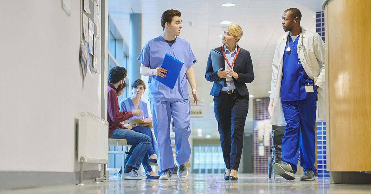 Doctor, nurse, and hospital leader walking down hall.